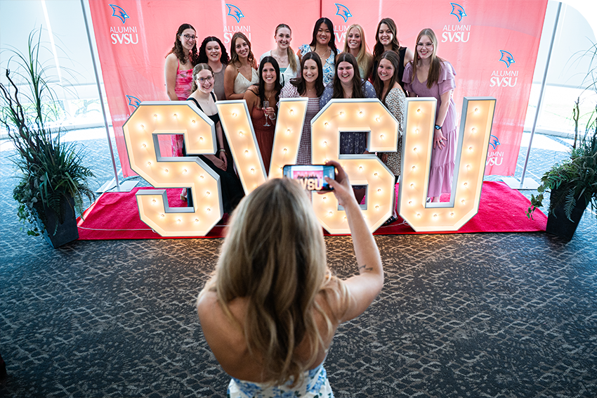 Group of graduates posing behind SVSU letters at senior toast